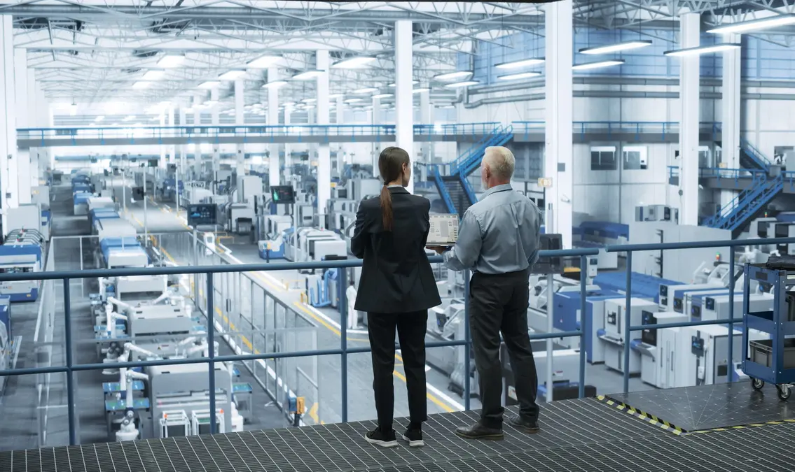 A business man and a woman overlooking a production facility