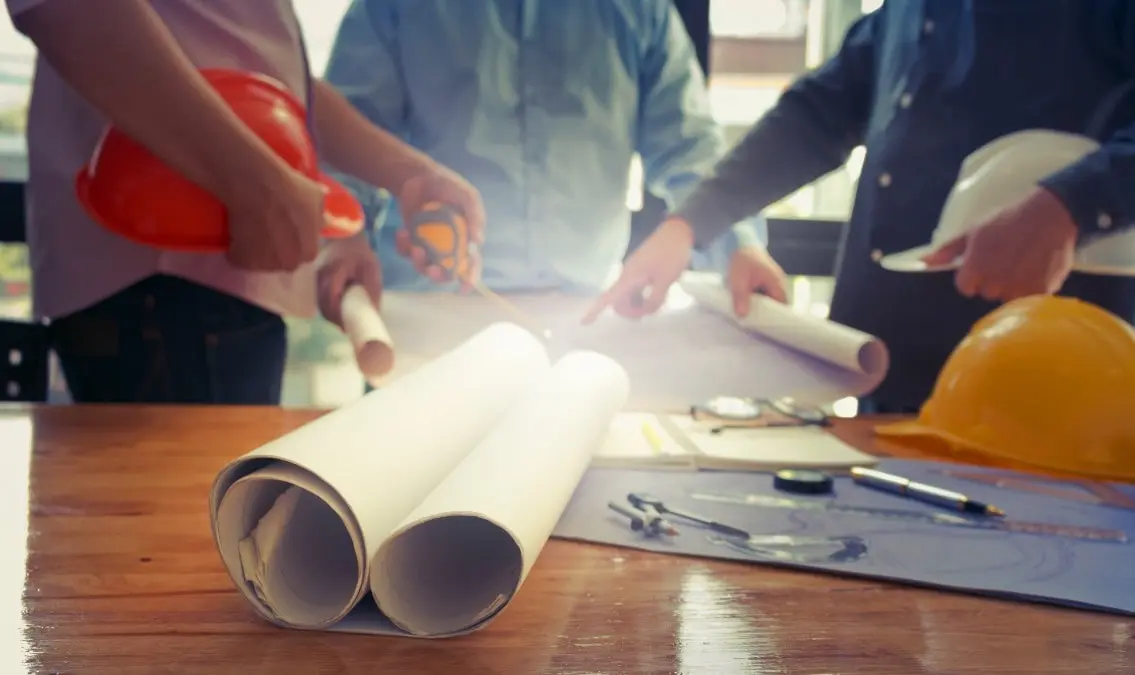 Engineers and technicians meeting with blueprints on a table