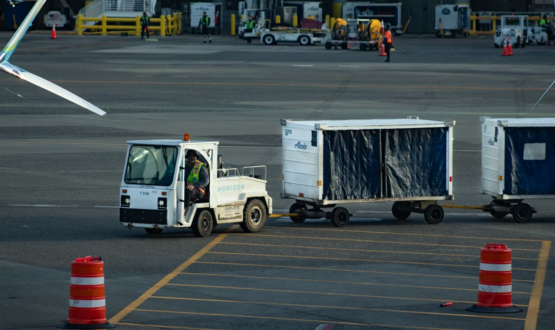 A small airport ground vehicle (baggage tug) pulling luggage carts