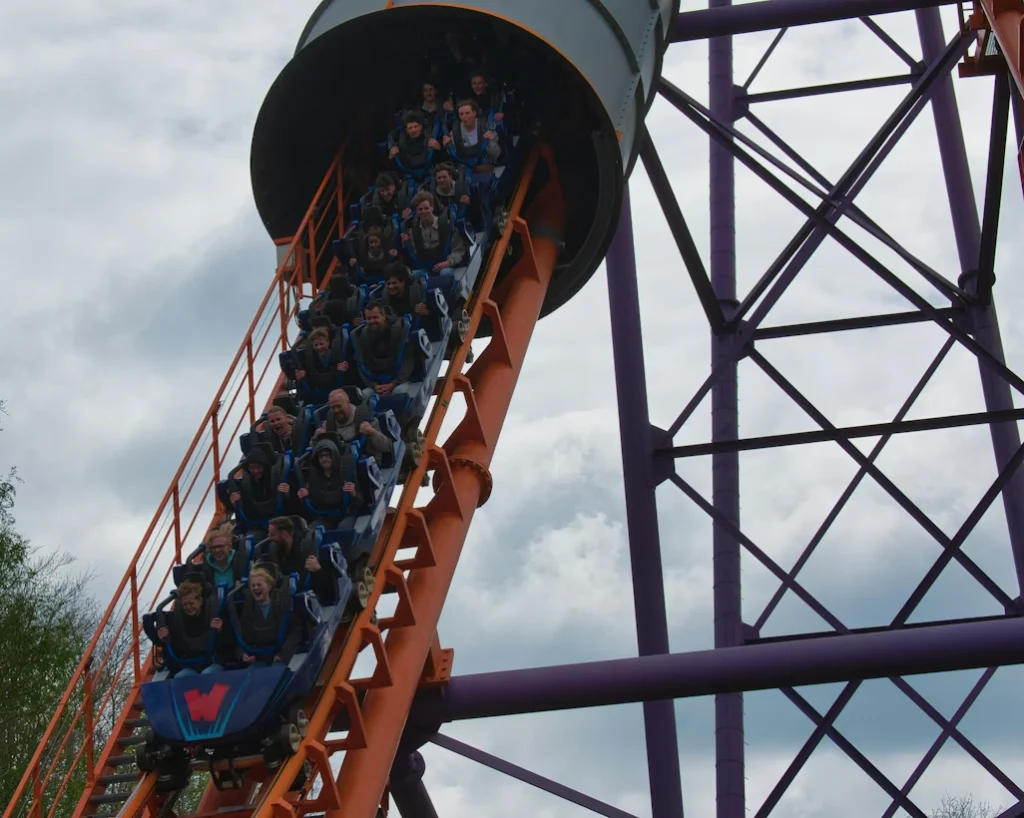Roller coaster with riders descending at an amusement park