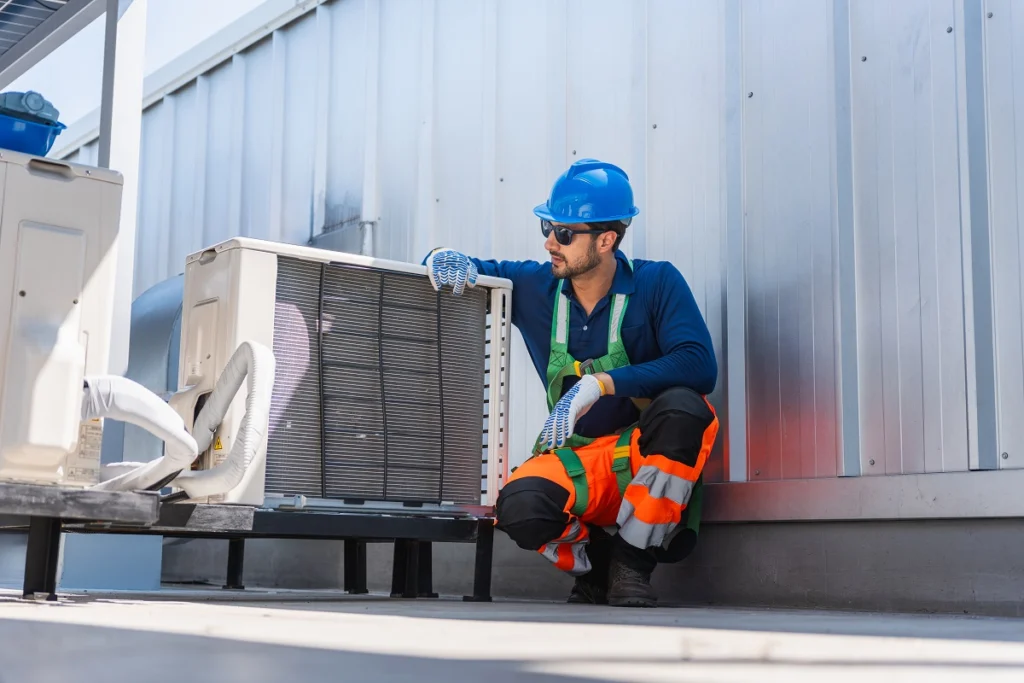 HVAC technician inspecting rooftop equipment as part of preventive maintenance and AI-driven asset management operations